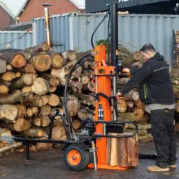 a machine with a wheel and wheels in front of a pile of logs