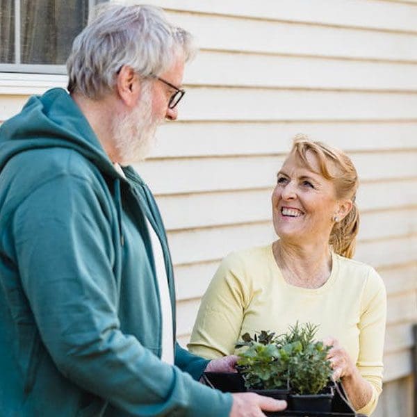 pareja feliz jardinería sosteniendo planta en maceta