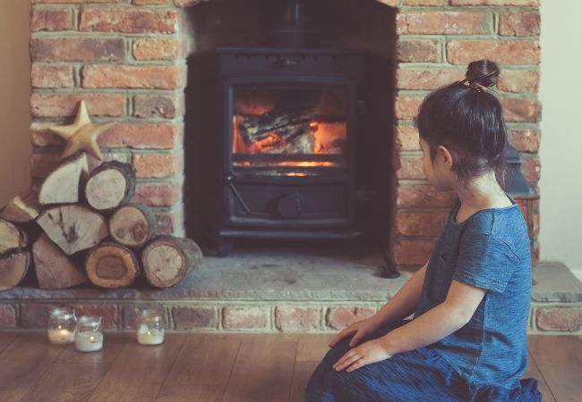 A child sitting by a wood stove