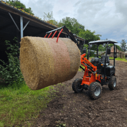 a tractor lifting a large bale of hay